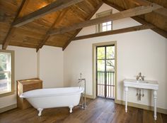 a large bathroom with wooden floors and white fixtures