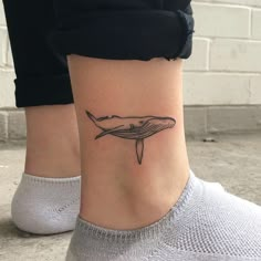 a woman's foot with a small tattoo of a whale on the side of her leg