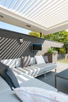 an outdoor living area with white couches and grey tables on the side of it