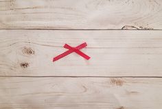 a piece of red ribbon on top of white wood with the end cut out to resemble a cross