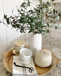 there is a vase with some green leaves on it next to dishes and utensils