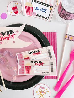 pink and black paper plates with movie tickets on them next to plastic forks, toothbrushes and other items