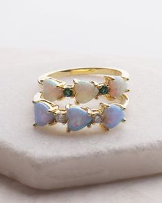 Opal Hearts Ring The Opal Hearts Ring features stunning opal hearts, accented with sparkling cubic zirconia and a vibrant emerald stone. This elegant ring is sure to make a statement and add a touch of sophistication to any outfit. Expertly crafted with high-quality materials, it is a must-have for any jewelry collection. DETAILS: 14k Gold Vermeil Synthetic Opal CZ and Synthetic Emerald Heart shape stones Opal Heart Ring, Resort Jewelry, Backpack Gift, Synthetic Opal, Beauty Clothes, Emerald Stone, Elegant Ring, Fine Jewellery Earrings, Mom Outfits