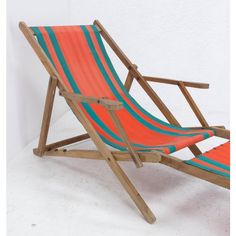 an orange and blue striped beach chair sitting on top of a white floor next to a wall