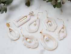 five pairs of earrings on a table next to flowers