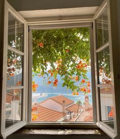 an open window looking out onto the water and houses with orange flowers on them are shown