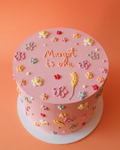 a pink cake decorated with flowers and the words marot is o'clock on it