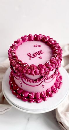 two tiered cake decorated with pink icing on a white plate next to napkins