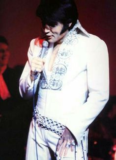 elvis presley singing into a microphone in front of people