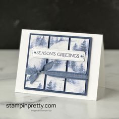 a close up of a card on a table with snow covered trees in the background