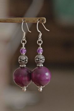 two purple beads are hanging from a pair of earrings