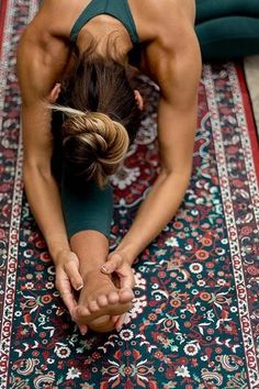 a woman in a green top doing yoga on a colorful rug with her hands together