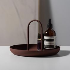 a bottle of lotion sitting on top of a brown tray next to a metal holder