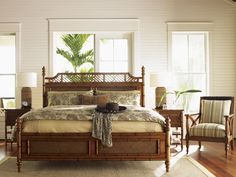 a large bed sitting in a bedroom on top of a hard wood floor next to two windows