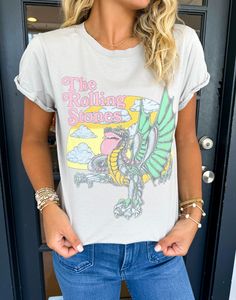 Introducing The Rolling Stones Dragon Tee, a must-have for any music lover. Crafted with a distressed design and short sleeves, this graphic tee boasts a stylish and edgy look. Perfect for concerts or everyday wear, it's a versatile addition to any wardrobe. Show off your love for the iconic band in style. Lilli is wearing a size Small. Height is 5’3, Bust is 32”, Waist 26”, and Hips 33”. Rock And Roll Cotton T-shirt With Graphic Print, Casual Graphic Print T-shirt For Concerts, Edgy Short Sleeve T-shirt With Band Logo, Trendy Crew Neck Tops For Music Festival, Trendy Acid Wash T-shirt For Concert, Band Merch Graphic T-shirt For Music Festival, Summer Distressed Band Merch T-shirt, Crew Neck Graphic Print Top, Trendy Band Logo T-shirt For Concerts