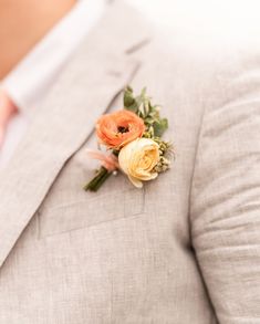 an orange boutonniere on the lapel of a man in a gray suit