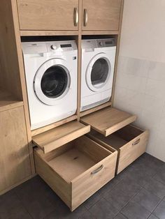 a washer and dryer in a small room with wooden cabinet drawers on the floor