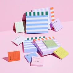 several colorful sticky notes laid out on top of each other next to a pink background