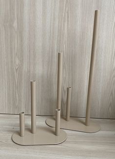 three beige candlesticks are standing in front of a wooden wall