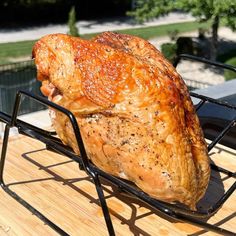 a large piece of meat sitting on top of a metal rack next to a wooden table