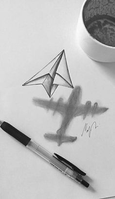 a cup of coffee next to a drawing of a plane and a paper airplane on a table