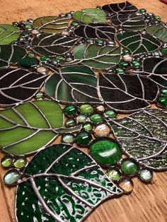 green and black stained glass leaves on a wooden table