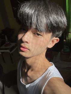 a young man with grey hair is looking at the camera while wearing a white tank top