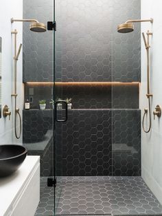 a black and white bathroom with hexagonal tiles on the walls, an oval sink and a glass shower door