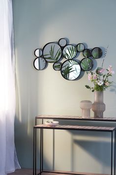 a table with a vase and mirror on it next to a wall mounted planter