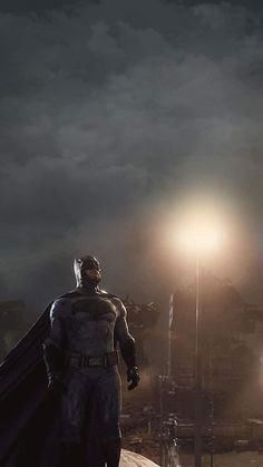 a man dressed as batman standing in front of a dark sky with light shining on him