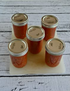 four jars of tomato sauce sitting on top of a cutting board