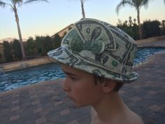 a young boy wearing a hat made out of dollar bills in front of a swimming pool