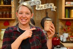 a woman holding a jar of food in her hand and pointing to it with the finger