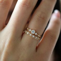 a woman's hand with three different rings on top of her finger and the other ring