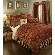 a bed in a bedroom with red and gold comforter set on top of it