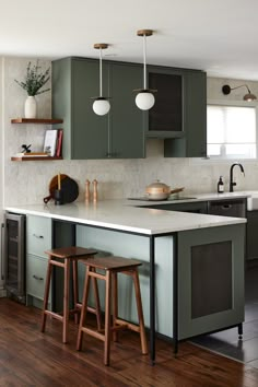 a kitchen with green cabinets and stools