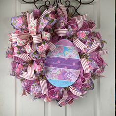 a purple wreath with pink and white bows hanging on the front door, next to a blue fire hydrant