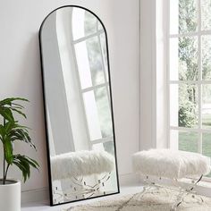 a mirror sitting on top of a white floor next to a plant