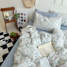 an unmade bed with blue and white flowers on it, next to a checkered floor