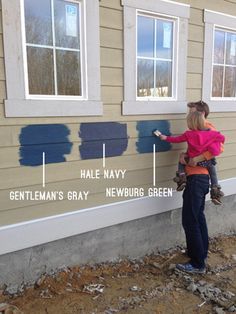 a woman is painting the side of a house with blue paint and she has her hands on the wall