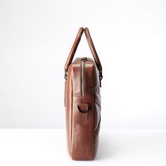 a brown leather bag sitting on top of a white table