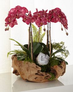 pink orchids and ferns in a wooden bowl