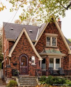 a brick house with a brown front door and two story windows on the second floor