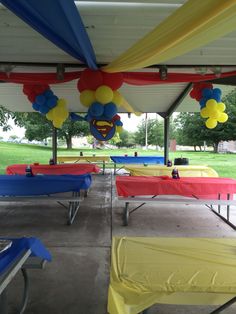 some tables and chairs covered with balloons in the shape of superman's face on them