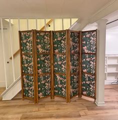 a room divider sitting on top of a hard wood floor next to a stair case