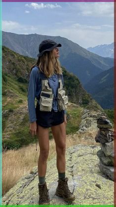 a woman standing on top of a mountain with her back to the camera and wearing hiking gear