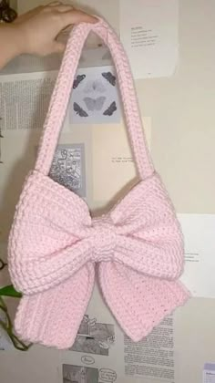 a pink purse with a large bow on the front hanging from it's side