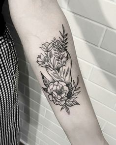 a black and white photo of a flower tattoo on the right arm, with leaves around it