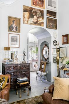 a living room filled with furniture and pictures on the wall above it's doorway