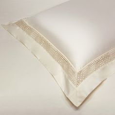 a white pillow with an embroidered border on the top and bottom, sitting on a plain surface